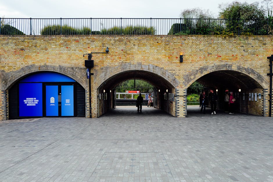 A brick archway structure with three distinct openings serves as an entrance or passageway at a London railway station, with the central arch being slightly larger than the two flanking arches. The br